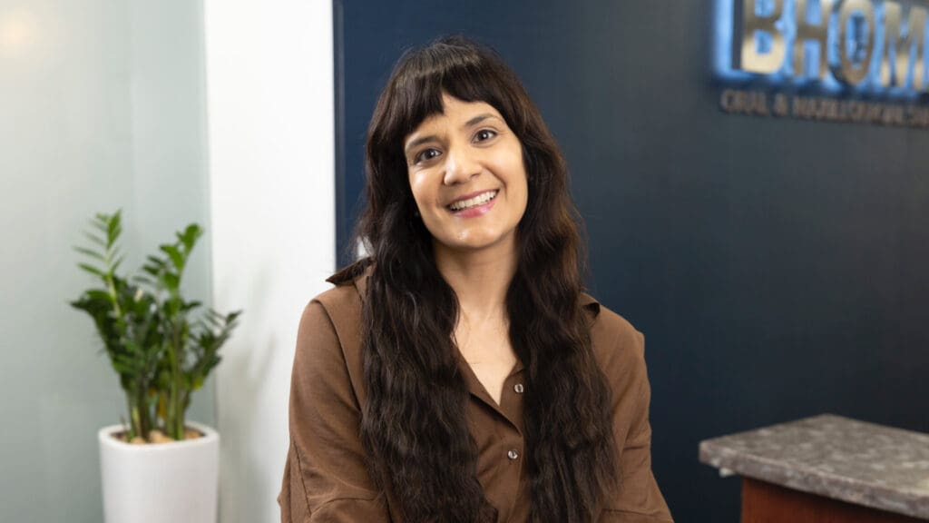 A woman with long hair and brown shirt smiling.