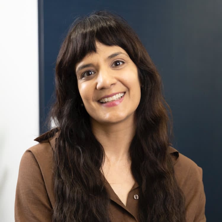 A woman with long hair and bangs smiles for the camera.