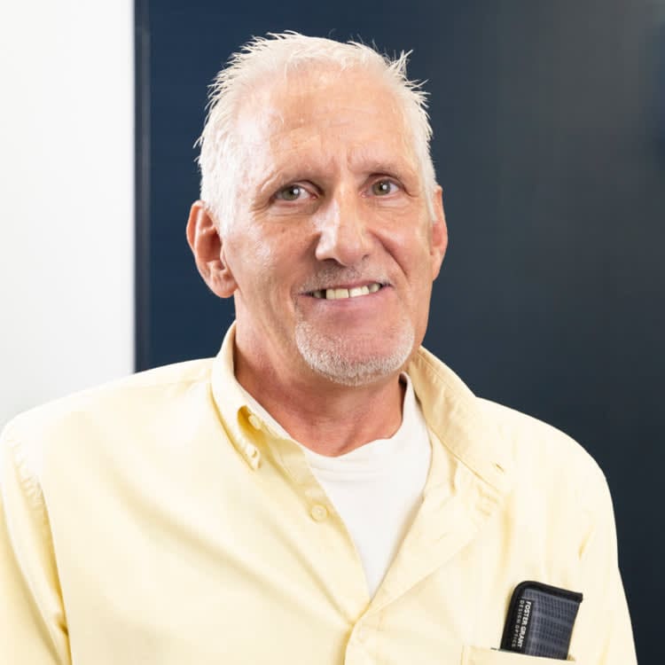 A man with white hair and a yellow shirt.